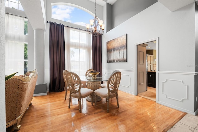 dining area featuring light wood-type flooring, a high ceiling, and a chandelier