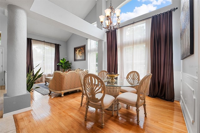 dining area with lofted ceiling, light hardwood / wood-style floors, a healthy amount of sunlight, and a notable chandelier