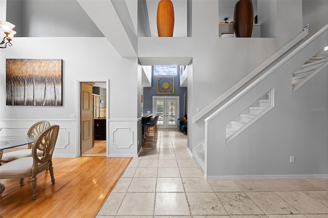 foyer entrance with french doors, a high ceiling, and light hardwood / wood-style flooring