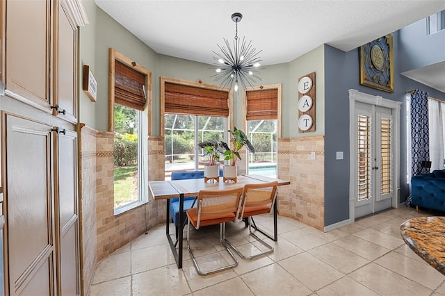 tiled dining space featuring a textured ceiling, tile walls, and a chandelier