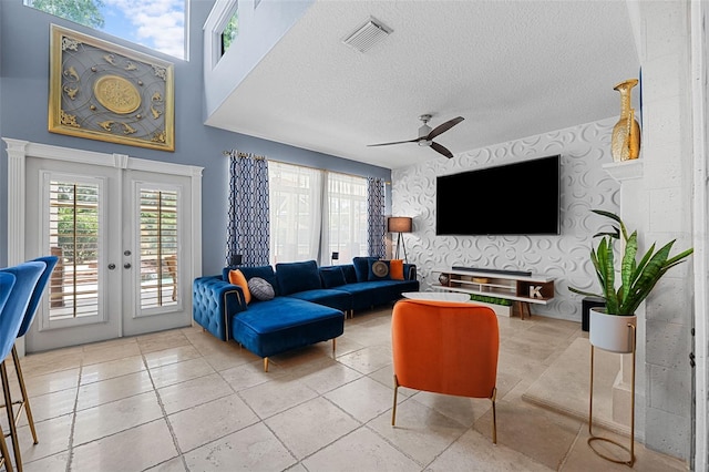 tiled living room featuring ceiling fan, a textured ceiling, and french doors