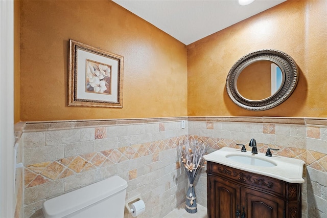 bathroom with vanity, tile walls, and toilet