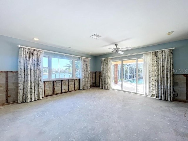 unfurnished living room with concrete flooring, a water view, and ceiling fan