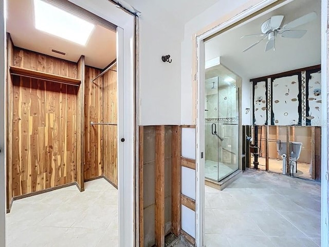 bathroom with tile patterned flooring, ceiling fan, wooden walls, and a shower with shower door