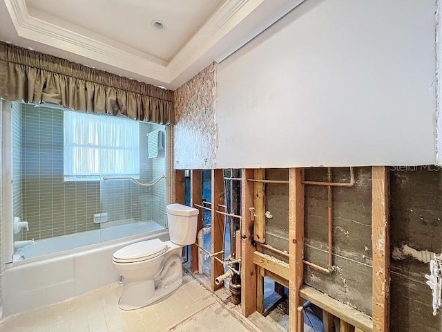 bathroom featuring tiled shower / bath combo, tile patterned floors, toilet, a tray ceiling, and ornamental molding