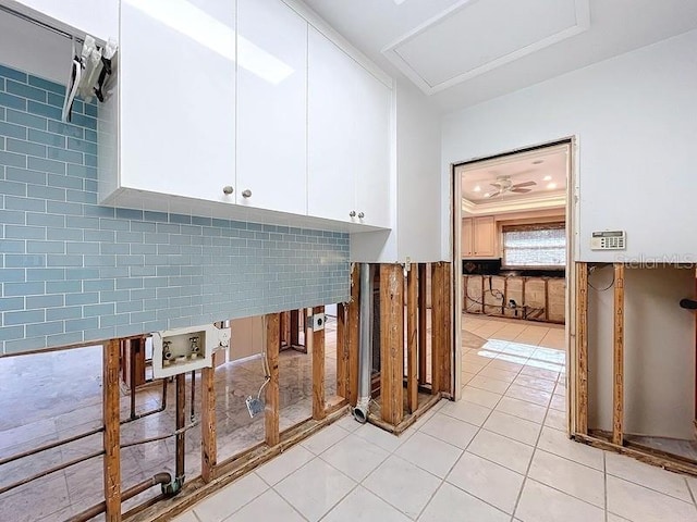 interior space featuring cabinets, hookup for a washing machine, light tile patterned floors, ornamental molding, and tile walls