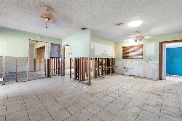 unfurnished room with ceiling fan and a textured ceiling