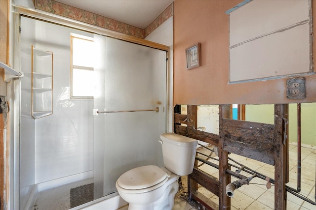 bathroom with tile patterned flooring, toilet, and a shower with shower door