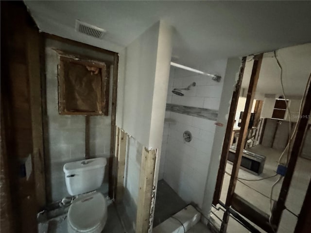 bathroom featuring a shower, toilet, and tile walls