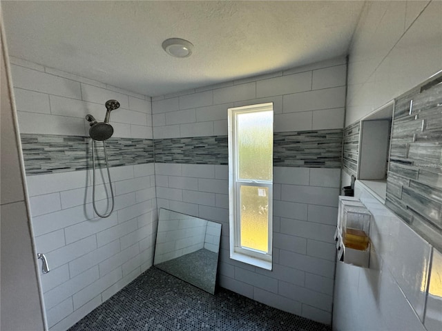 bathroom with a tile shower, a textured ceiling, and tile walls