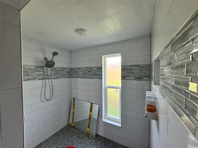 3960 Headsail Dr, New Port Richey, FL 34652 - bathroom featuring a tile shower, tile walls, and a textured ceiling
