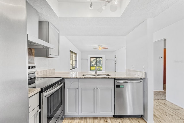 kitchen featuring a textured ceiling, light stone countertops, light wood-type flooring, and stainless steel appliances