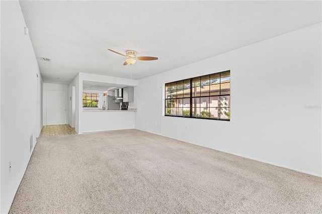 unfurnished living room featuring ceiling fan, carpet floors, and a textured ceiling