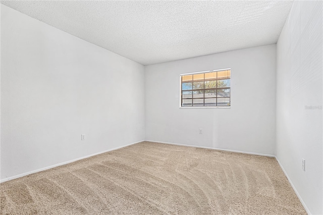 carpeted empty room featuring a textured ceiling