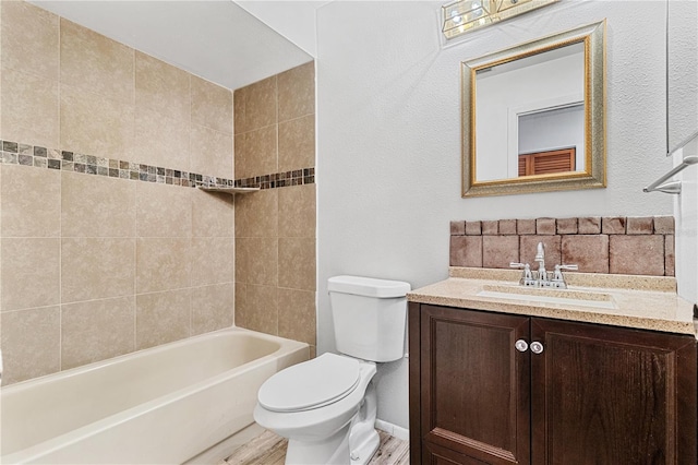 full bathroom featuring hardwood / wood-style flooring, vanity, toilet, and tiled shower / bath