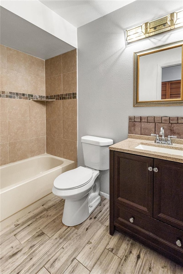 full bathroom featuring hardwood / wood-style floors, vanity, toilet, and tiled shower / bath