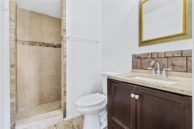 bathroom featuring tiled shower, vanity, hardwood / wood-style flooring, and toilet