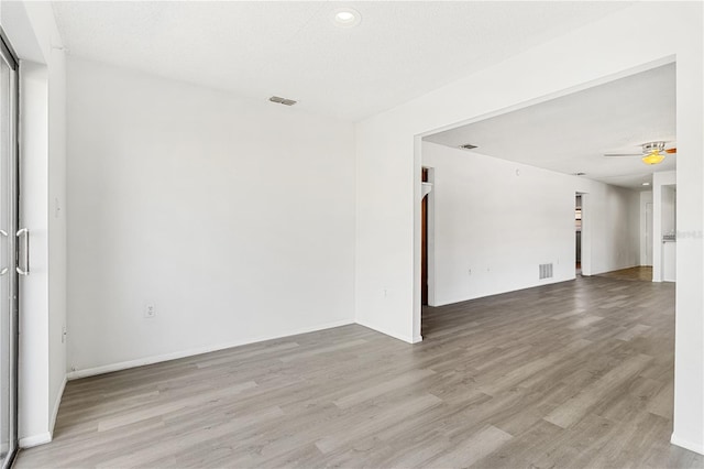 unfurnished room featuring wood finished floors, visible vents, and baseboards