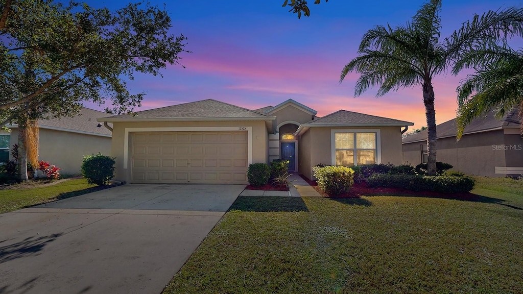 ranch-style home with a garage and a yard