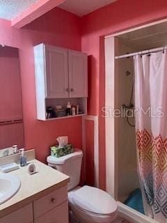 bathroom featuring a shower with shower curtain, vanity, and toilet