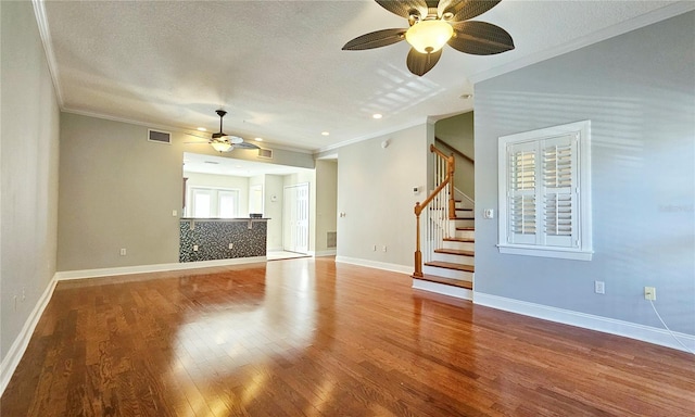 unfurnished living room featuring wood-type flooring, a textured ceiling, and ornamental molding