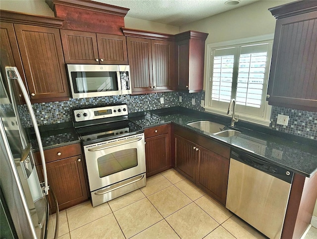 kitchen with sink, light tile patterned floors, backsplash, and appliances with stainless steel finishes