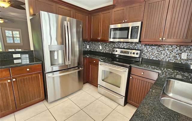 kitchen featuring sink, ceiling fan, decorative backsplash, dark stone countertops, and stainless steel appliances