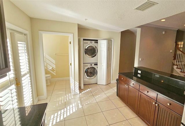 washroom featuring light tile patterned floors, a textured ceiling, and stacked washer / dryer