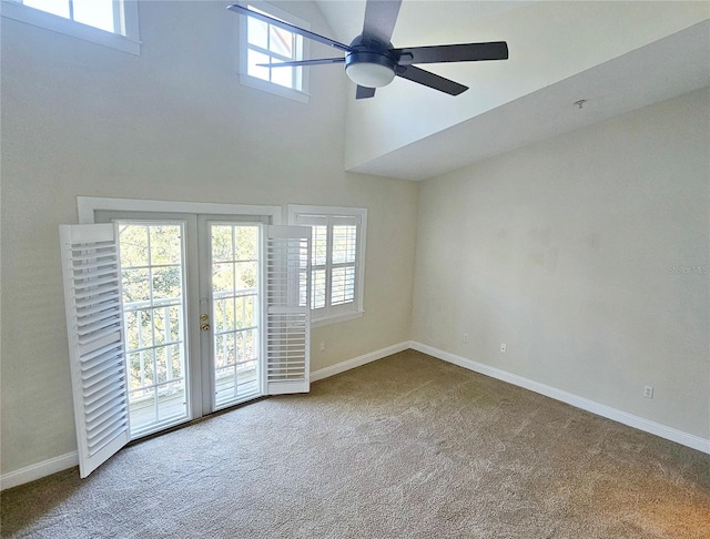 carpeted empty room featuring ceiling fan, a healthy amount of sunlight, and a high ceiling