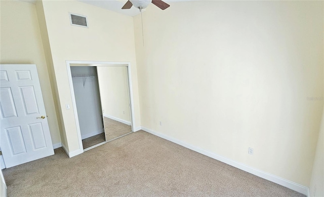 unfurnished bedroom featuring ceiling fan, light carpet, and a closet