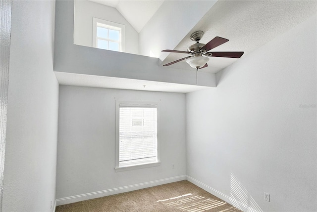 carpeted empty room with ceiling fan, a healthy amount of sunlight, and vaulted ceiling