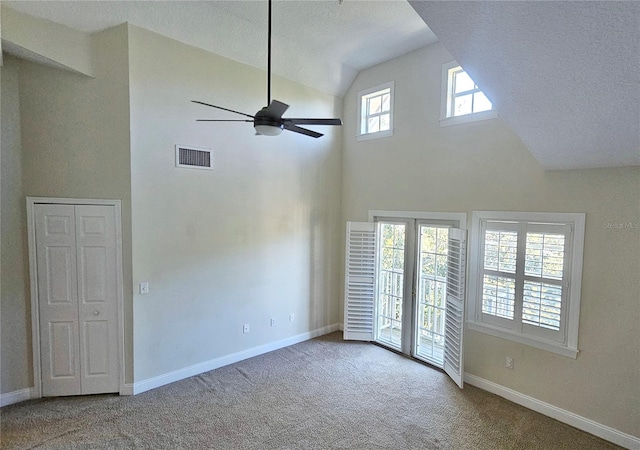 carpeted spare room featuring a textured ceiling, high vaulted ceiling, and ceiling fan