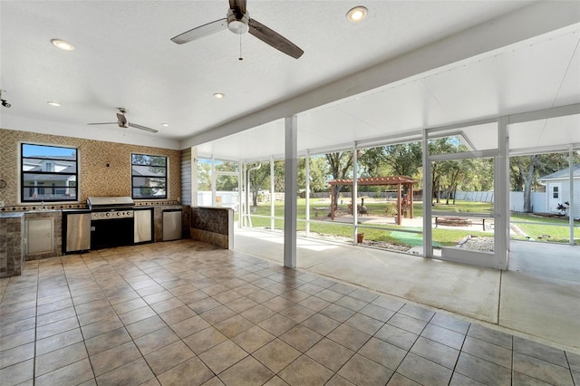 interior space with a pergola, ceiling fan, exterior kitchen, and area for grilling