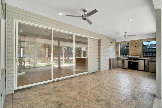 view of patio with an outdoor kitchen, ceiling fan, and a grill