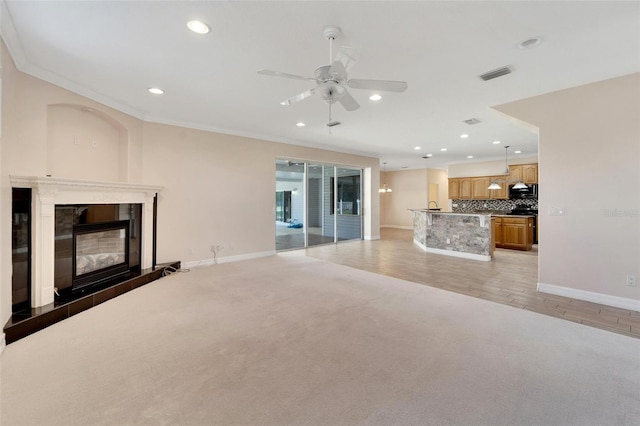 unfurnished living room featuring light hardwood / wood-style flooring, ceiling fan, and ornamental molding