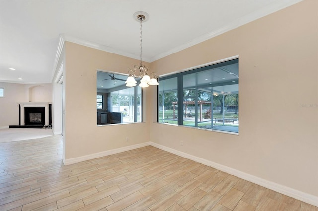 unfurnished dining area featuring ceiling fan with notable chandelier and crown molding