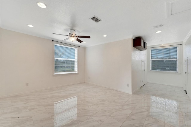 empty room featuring a textured ceiling, ceiling fan, and crown molding