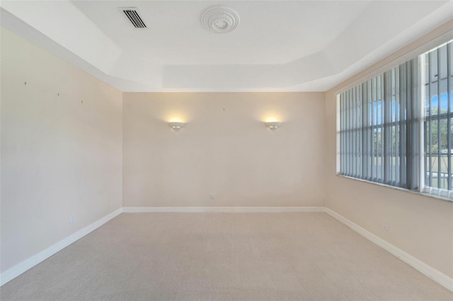 empty room with a tray ceiling and carpet flooring