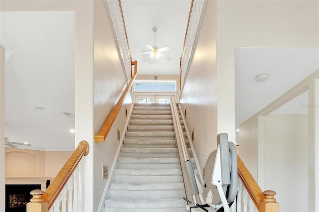 stairs featuring ceiling fan and a towering ceiling