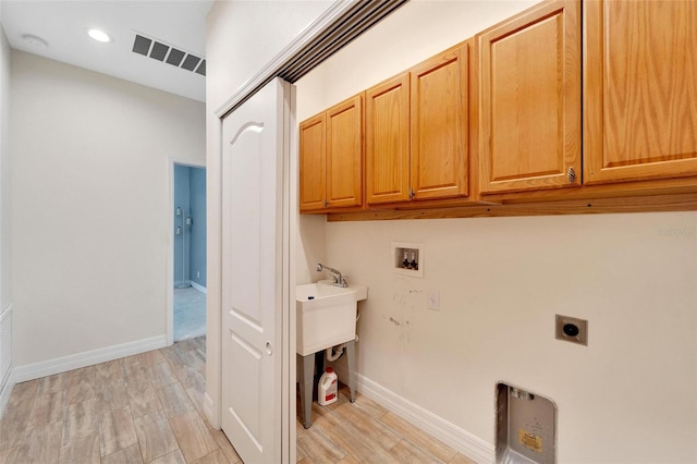 clothes washing area featuring electric dryer hookup, hookup for a washing machine, cabinets, and light wood-type flooring