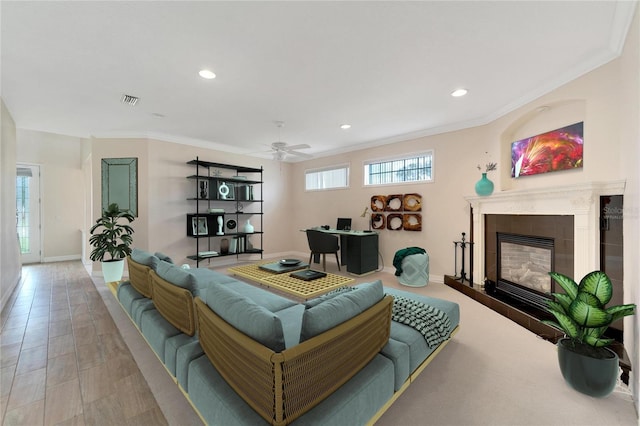 living room with ceiling fan, ornamental molding, and a tiled fireplace