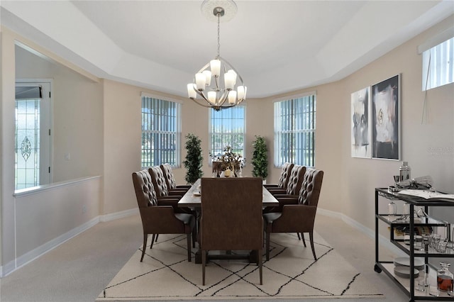 carpeted dining area featuring a tray ceiling, a healthy amount of sunlight, and a chandelier