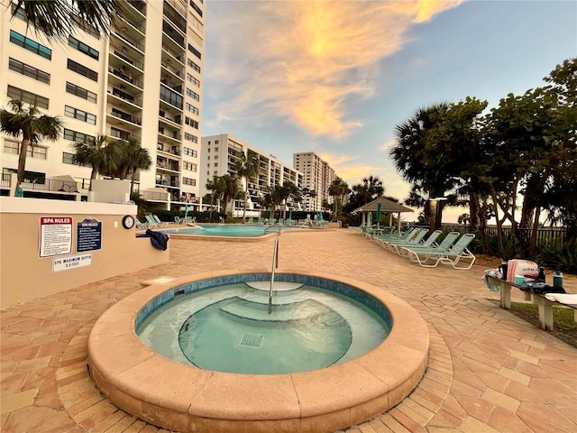 pool at dusk featuring a gazebo, a patio area, and a community hot tub