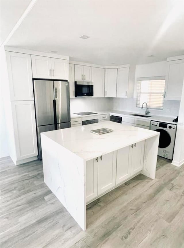 kitchen featuring white cabinets, appliances with stainless steel finishes, a center island, and light stone counters