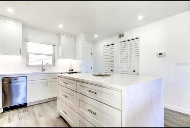 kitchen featuring white cabinetry, a center island, stainless steel dishwasher, and sink