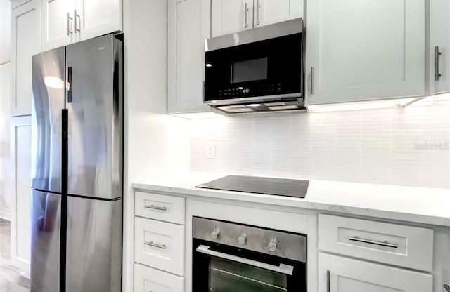 kitchen with white cabinets, backsplash, stainless steel appliances, and light stone counters