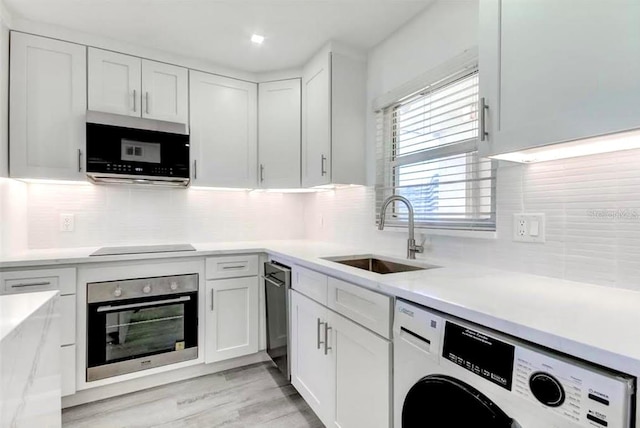 kitchen featuring decorative backsplash, appliances with stainless steel finishes, sink, white cabinets, and washer / dryer