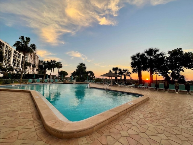 pool at dusk featuring a patio