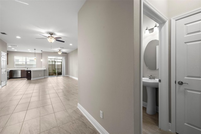 hall featuring light tile patterned floors and sink