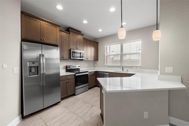 kitchen featuring sink, kitchen peninsula, pendant lighting, light tile patterned floors, and appliances with stainless steel finishes